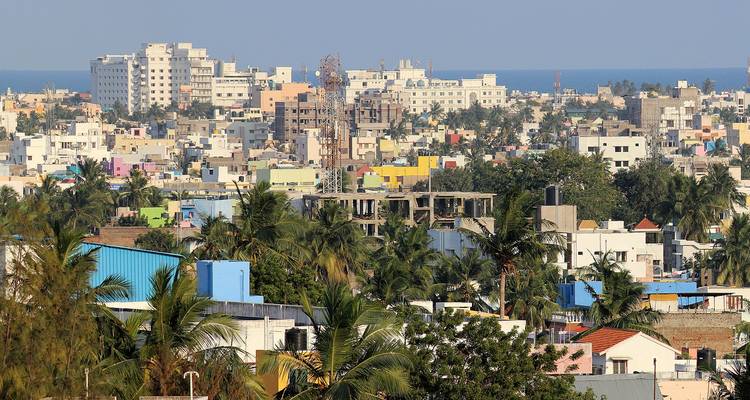 Cityscape with colorful buildings and palm trees near the sea.