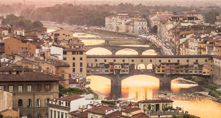 La douce lumière du coucher de soleil se reflète sur l'Arno et le Ponte Vecchio avec plusieurs ponts à Florence.