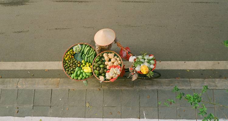 Vue de haut d'un vendeur à bicyclette chargé de produits frais garés dans une rue tranquille.