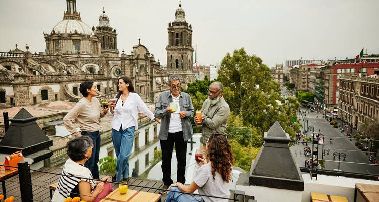 Friends enjoy drinks on a rooftop terrace overlooking an ornate historic cathedral.