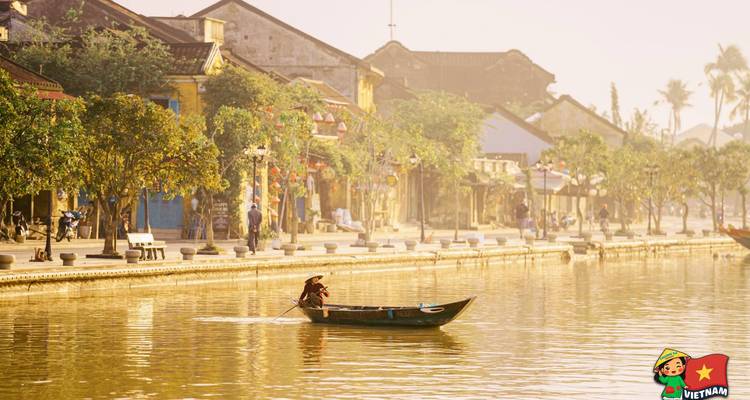 Un bote de madera solitario en un río tranquilo con casas históricas coloridas.