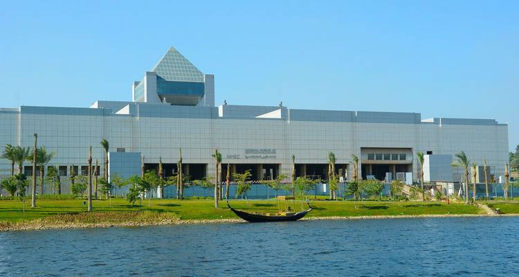 Modern building with river and green landscape in the foreground.