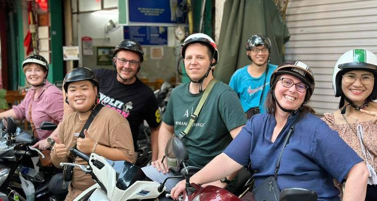 Grupo de amigos preparándose para andar en scooters, usando cascos y sonriendo.