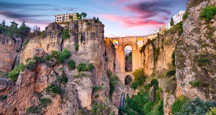 Dramatic Puente Nuevo stone bridge spanning a deep gorge at colorful sunset in Ronda.