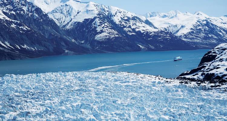 Calving glacier edge and snow-capped coastal mountains along the icy waters of Glacier Bay.