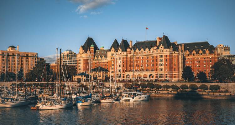 Victoria’s Inner Harbour with sailboats moored in front of the historic Fairmont Empress Hotel at golden hour.