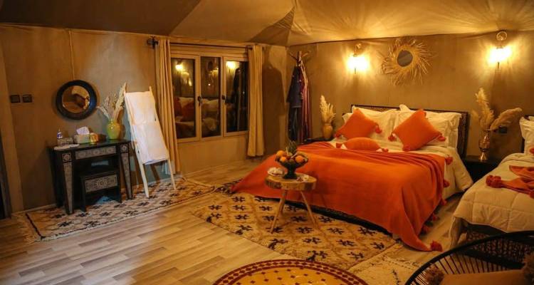 Cozy desert-style tent accommodation with warm lighting, patterned rugs and vibrant cushions.