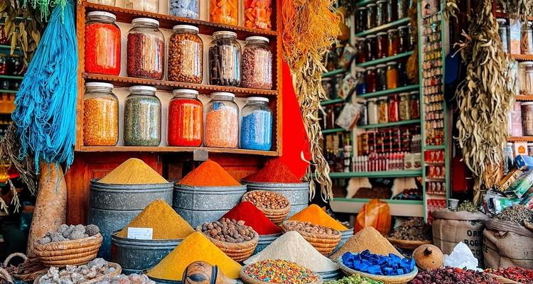 Colorful pyramids of spices, herbs and pigments fill a lively Moroccan market stall.