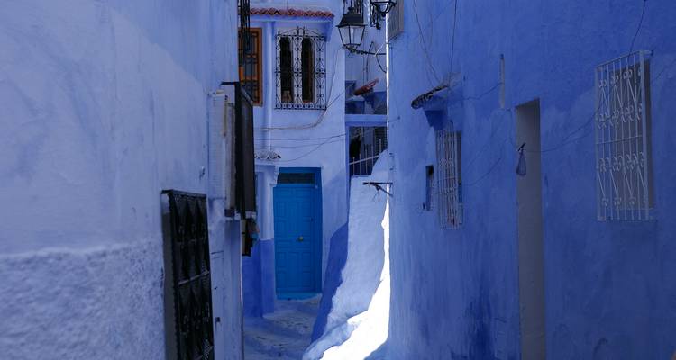 Bright blue alleyway with white-trimmed doors in the medina of Chefchaouen.