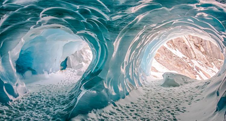 Des vagues de glace turquoise forment un double tunnel surréaliste à l'intérieur d'une grotte glaciaire.