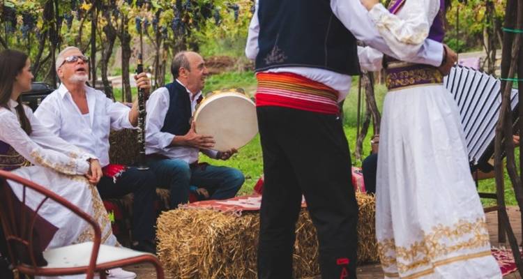 Des habitants en tenue traditionnelle jouant de la musique et dansant autour de balles de foin lors d'une célébration en plein air.