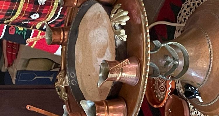 Service à café bulgare traditionnel avec pots en cuivre et plateau décoratif sur une petite table.