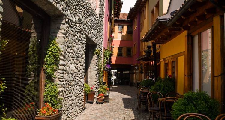 Charmante schmale Kopfsteinpflastergasse gesäumt von bunten Gebäuden, Steinmauern und Straßencafés.