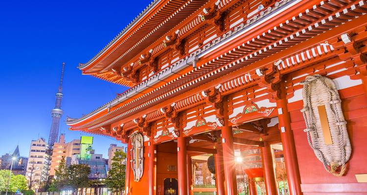 Night-lit Senso-ji temple with Tokyo Skytree shining behind it against a deep blue sky.