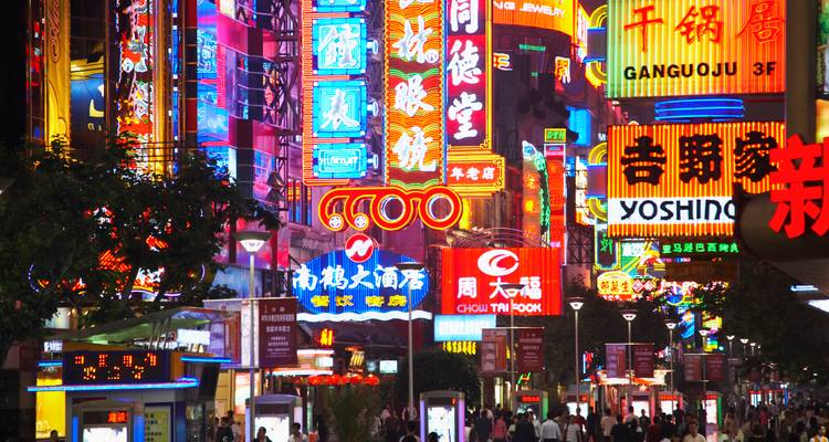 Bustling neon-lit shopping street packed with people under vibrant Chinese signage at night.