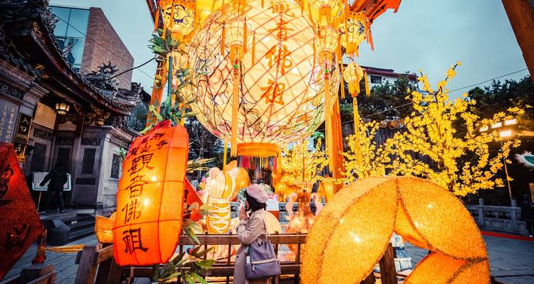 Traveler admires a giant illuminated lantern and festive decorations during a night market celebration.