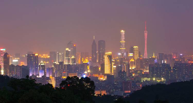 Panorama nocturno del horizonte de Guangzhou brillando con luces coloridas y cielo púrpura brumoso