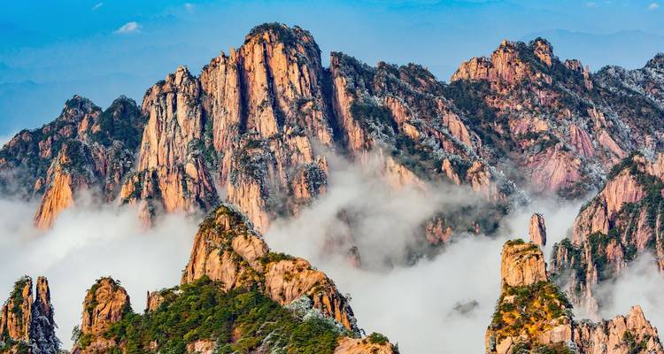 Les pics granitiques déchiquetés du Huangshan s'élèvent au-dessus des nuages tourbillonnants et des pins teintés d'automne.