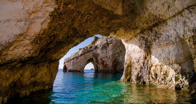 Zonnige kalkstenen bogen van de Blue Caves die weerspiegelen in de rustige turquoise zee.