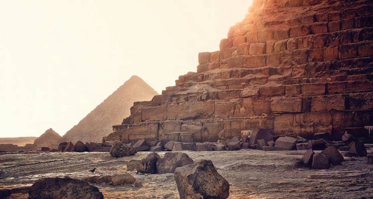 Stone blocks of the Great Pyramid glow in golden sunset light with a smaller pyramid beyond.