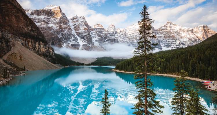 Le lac Moraine aux eaux cristallines reflète les pics enneigés aux contours déchiquetés et les sapins éternels du parc national de Banff.