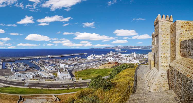 Vista amplia del puerto de Tánger, el puerto deportivo y las murallas de la fortaleza con el azul profundo del Estrecho de Gibraltar extendiéndose hasta el horizonte.