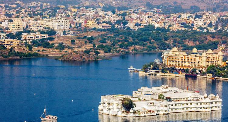 Hohe Aussicht auf die Stadt Udaipur und die umliegenden Seen mit Inselpalast und Hügeln im Hintergrund.
