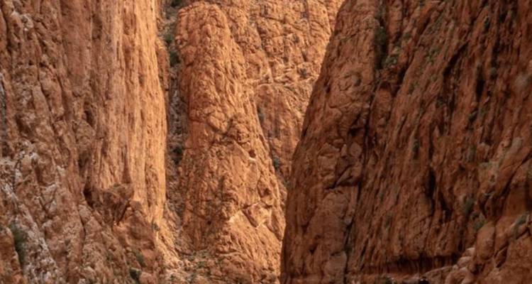 Steep reddish canyon walls with narrow passageway in Morocco’s Todra Gorge.