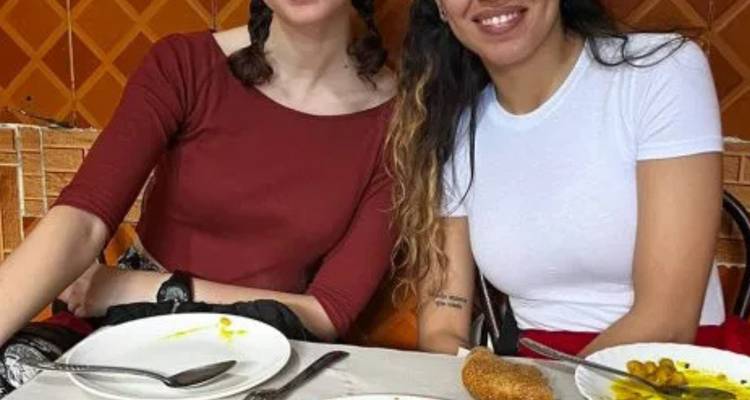 Two friends sharing a casual street meal with empty plates and olives.