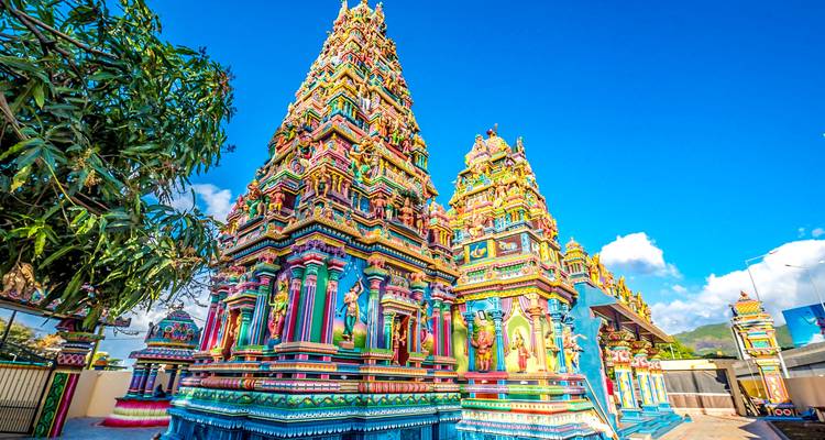Brightly coloured Hindu temple towers richly decorated against a clear blue sky