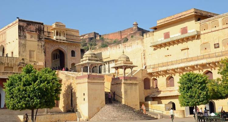 Besucher betreten das gelblich getönte Amber Fort durch ein verziertes Tor, das von kleinen Kuppelpavillons flankiert wird.