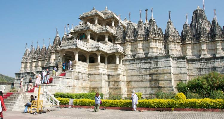Aufwendig geschnitzter Marmortempel mit mehreren Türmen und Besuchern, die rot-teppichbelegte Stufen hinaufsteigen.