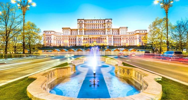 Palais du Parlement illuminé de Bucarest reflété dans une fontaine décorative au crépuscule.