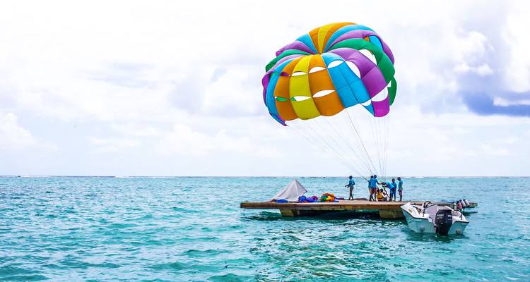Group preparing for colourful parasailing adventure from a floating platform on turquoise sea