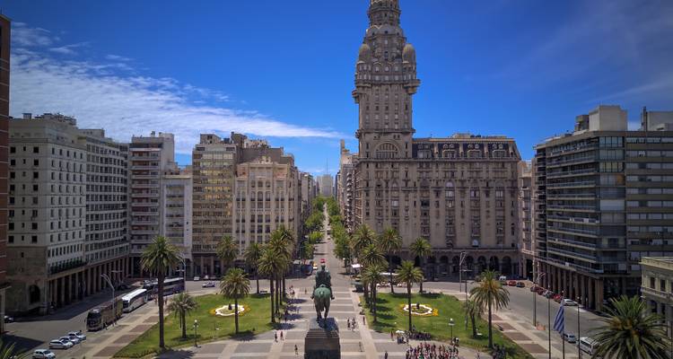 Vue aérienne de la Plaza Independencia avec le Palacio Salvo et l'avenue bordée de palmiers sous un ciel bleu profond