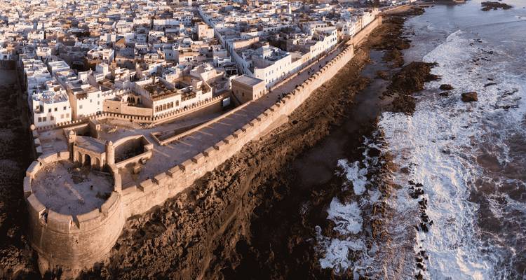 Vue panoramique aérienne des remparts fortifiés d'Essaouira s'étendant dans l'Atlantique avec les vagues qui se brisent en contrebas.
