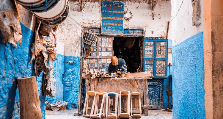 Artisan travaillant dans un atelier rustique peint en bleu dans la médina de Chefchaouen.