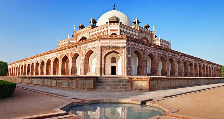 Perfectly symmetric view of Humayun’s Tomb with clear blue sky and reflecting pool.