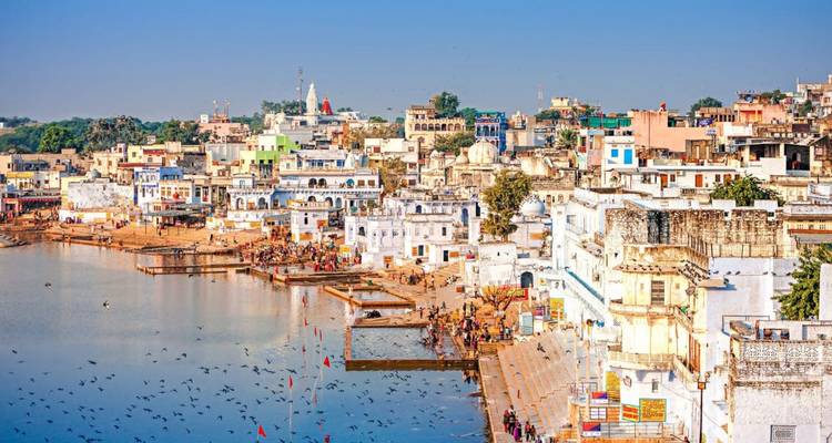 Panoramic lakeside view of Pushkar town with ghats, temples and bustling activity along the water.