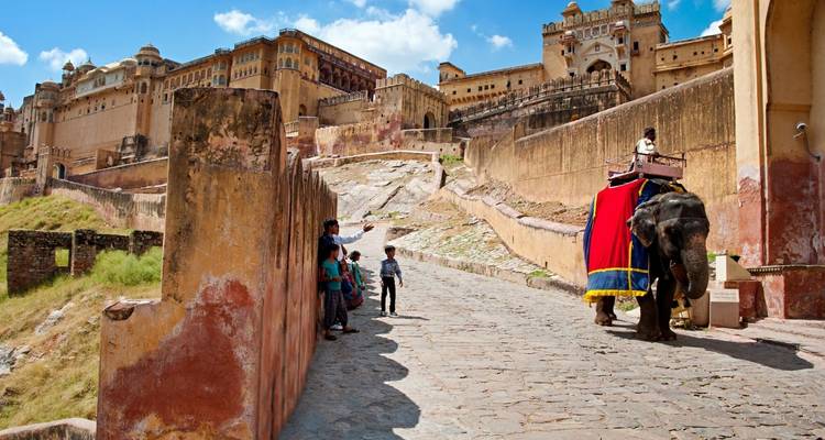 Visitors greet a decorated elephant on the ramparts of Amber Fort beneath bright blue skies.