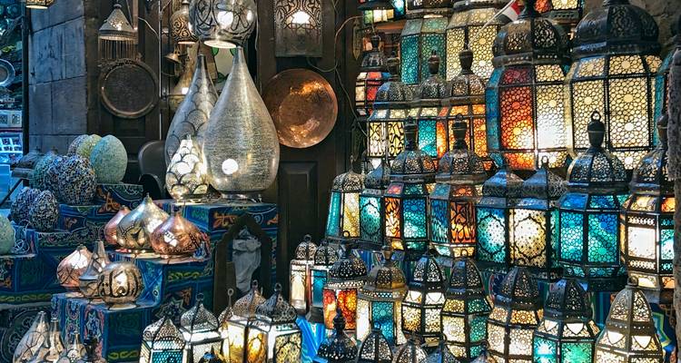 Colourful, intricately patterned lanterns and metalware stacked in a Cairo market stall.
