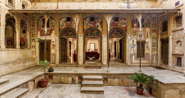 Kleurrijke gefreskode haveli binnenplaats met sierlijke bogen en beschilderde muren in Shekhawati.