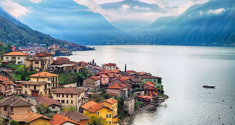 Misty morning view over charming lakeside villages and rolling hills on Lake Como.