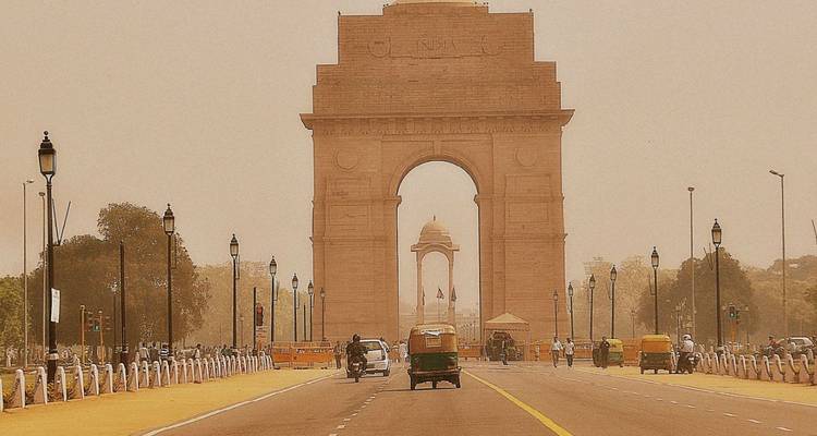Rechte weg die leidt naar het India Gate monument omlijst door nevel en straatlantaarns in Delhi.