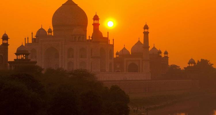 Silhouette du Taj Mahal brillant dans un coucher de soleil orange flamboyant au bord de la rivière Yamuna
