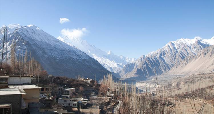 Vista sobre un pequeño pueblo respaldado por escarpados picos nevados y un profundo desfiladero