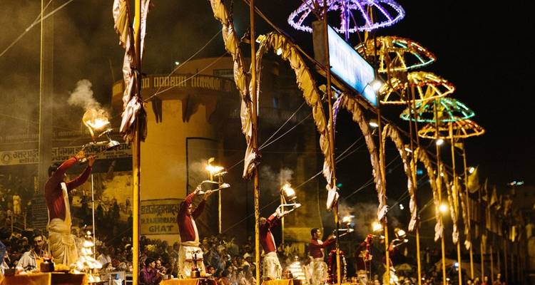 Evening Ganga Aarti ceremony with priests waving flaming lamps toward the river before a crowd
