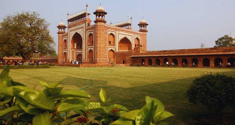 Grand red-sandstone gateway to the Taj Mahal complex bordered by manicured lawns