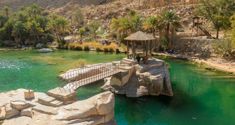 Emerald pools and palm groves surround a stone gazebo at Wadi Bani Khalid’s idyllic oasis.