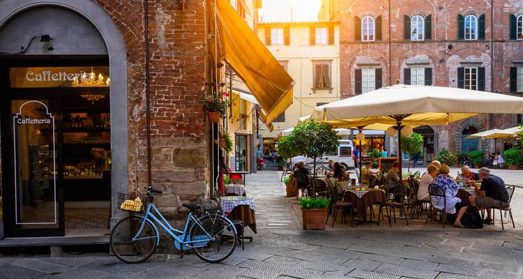 Charming Lucca piazza with outdoor café tables, bicycles and warm evening glow